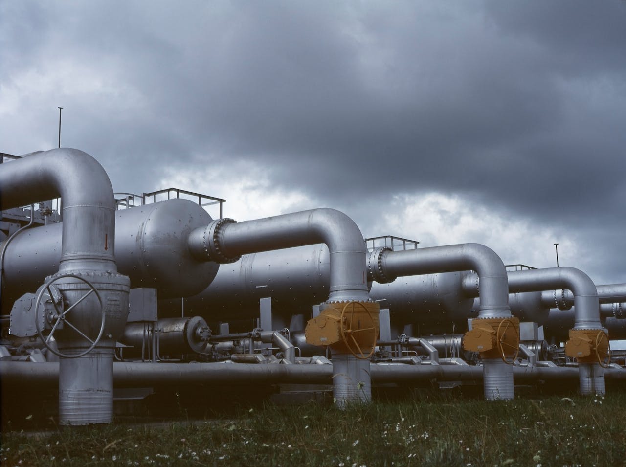 services-03 Gloomy industrial scene with metal pipes and valves under dark clouds.